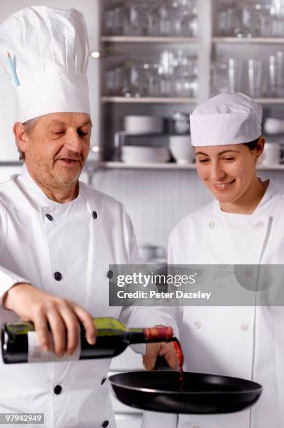 senior chef teaching trainee to flambe in kitchen - flambe stock pictures, royalty-free photos & images