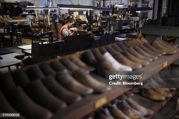 Worker makes boots past a shelf of wooden shoe patterns at the Dehner Co. Factory in Omaha, Nebraska, U.S., on Tuesday, June 5, 2018. Markit is...