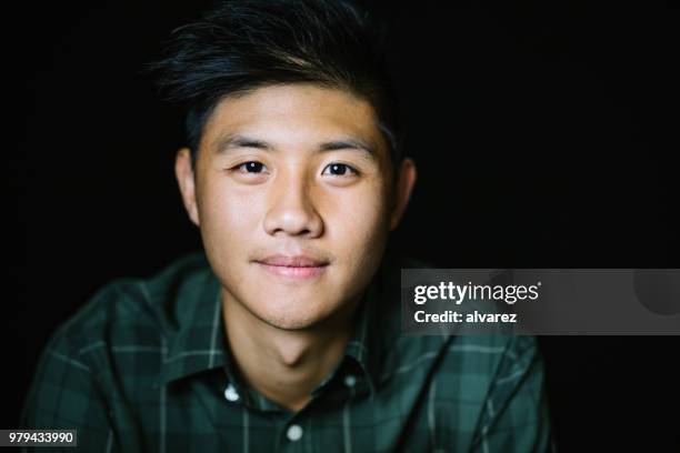 young man smiling on black background - black eye close up stock pictures, royalty-free photos & images