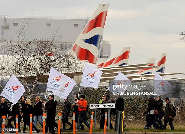 Striking British Airways cabin crew carry flags as they walk past BA aircraft on the final day of a three-day strike near London Heathrow airport, on...