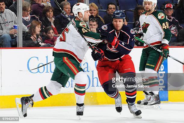 Defenseman Cam Barker of the Minnesota Wild checks defensman Marc Methot of the Columbus Blue Jackets on March 19, 2010 at Nationwide Arena in...