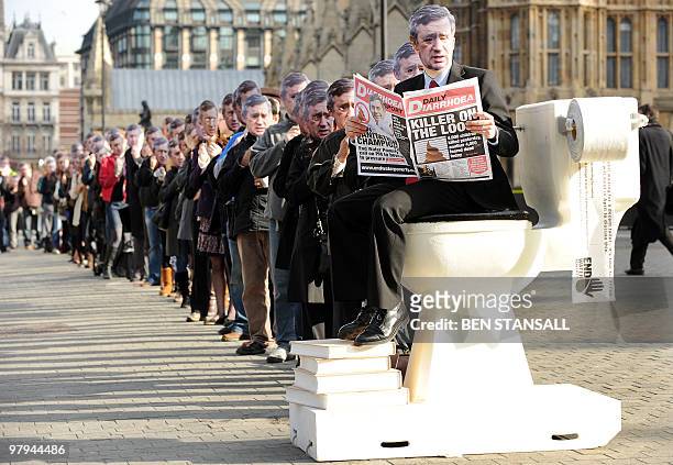 Protestors wearing masks depicting British Prime Minister Gordon Brown queue in front of a giant toilet outside the Houses of Parliament in London,...