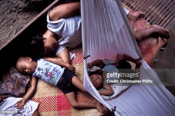 Remedios de la Cruz and her sleeping family at siesta time outside their hut/ house in the small fishing village of Busok Busok, Philippines.