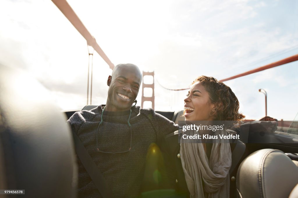 Couple cheering and laughing on the backseat of convertible car