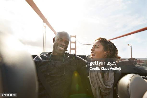 couple cheering and laughing on the backseat of convertible car - american tourist stock-fotos und bilder