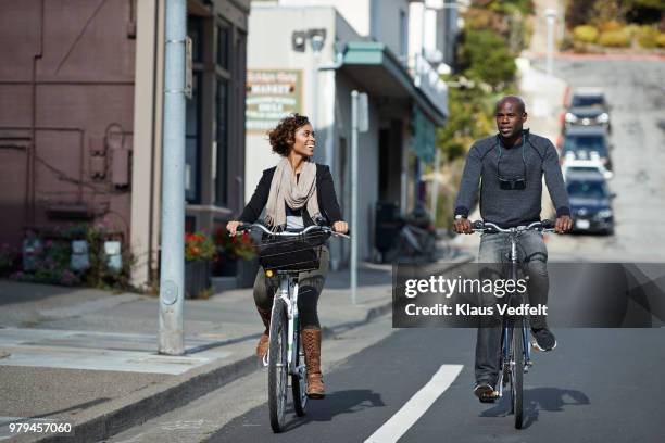couple using rental bikes in the small town sausalito - amerikaans dorpsleven stockfoto's en -beelden