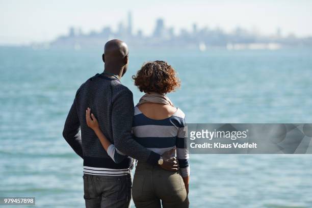 couple watching the san francisco skyline - arm around shoulder behind stock pictures, royalty-free photos & images