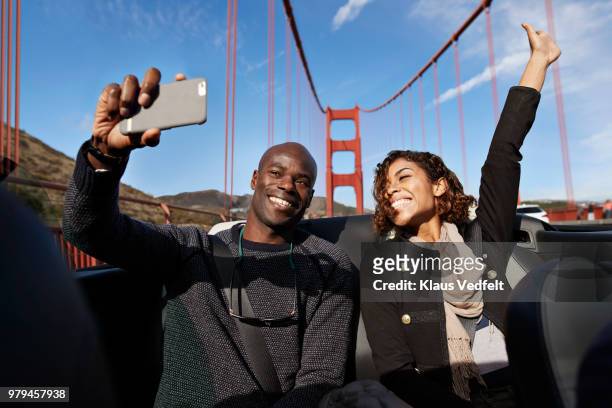 laughing couple making selfie on the back seat of convertible car - nordkalifornien stock-fotos und bilder