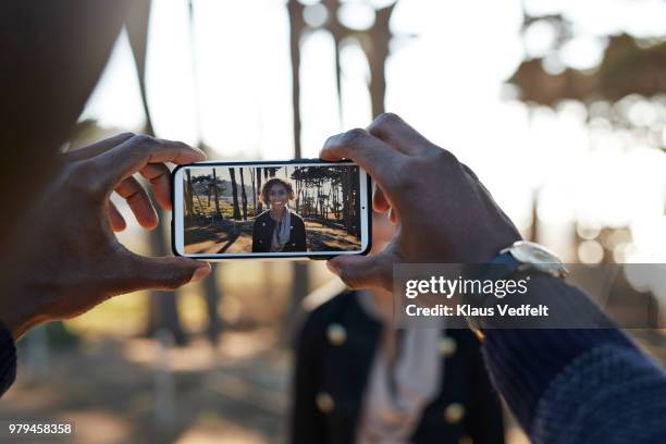 couple in nature park making photos of each other with smartphone - interracial wife photos stock-fotos und bilder