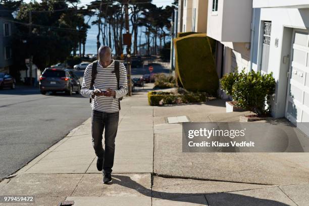 man walking on steep road and checking smartphone - san francisco design center stock pictures, royalty-free photos & images