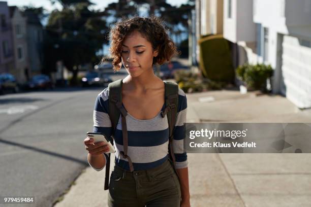 woman walking on steep road and looking at smartphone - women phone city facebook tourist stock pictures, royalty-free photos & images