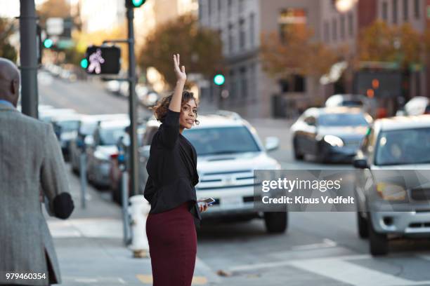 businesswoman hailing cab on the streets of san francisco - woman waving stock pictures, royalty-free photos & images