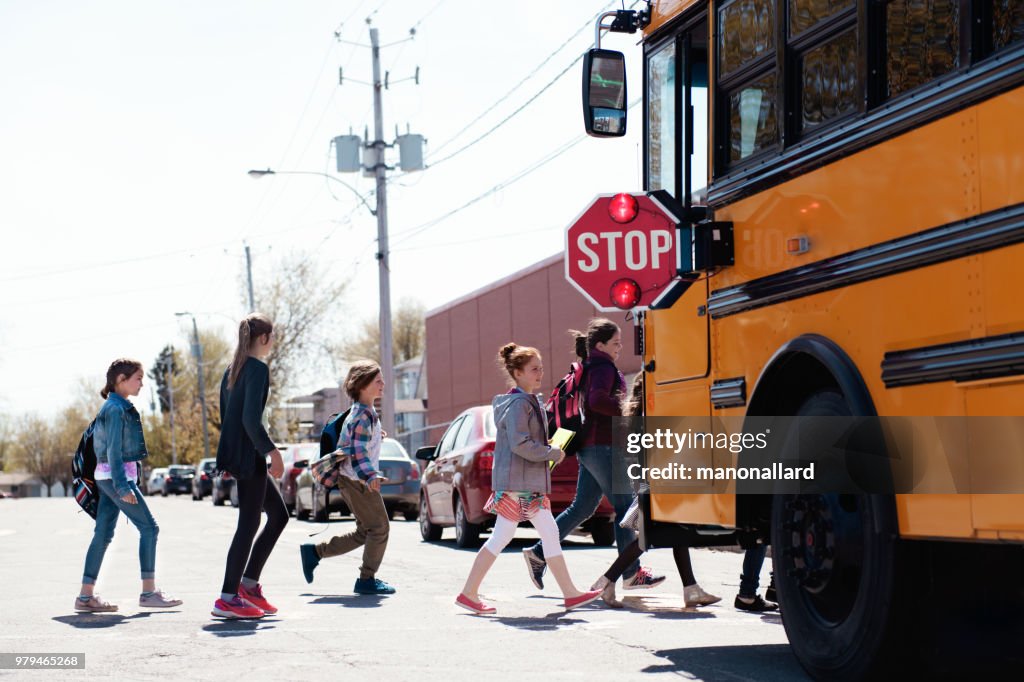 Group of elementary school kids getting in a school bus at school's out.