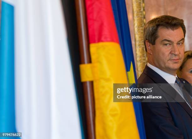 June 2018, Germany, Munich: Markus Soeder of the Christian Social Union , Premier of Bavaria, stands next to the Bavarian, German and European flag...