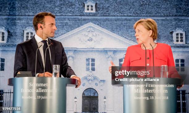 June 2018, Germany, Meseberg: German Chancellor Angela Merkel of the Christian Democratic Union and President of France, Emmanuel Macron, deliver...