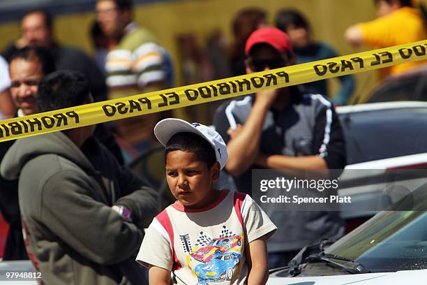 Boy looks out at a murder scene in which two men lay dead on March 22, 2010 in Juarez, Mexico. Both men, who were 18 and 34 years of age, were shot...