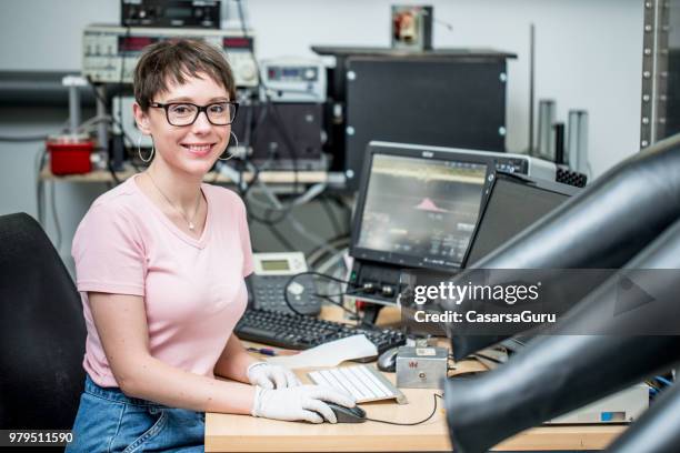 smiling female researcher measuring transient photocurrent in organic semiconductors - glove box stock pictures, royalty-free photos & images