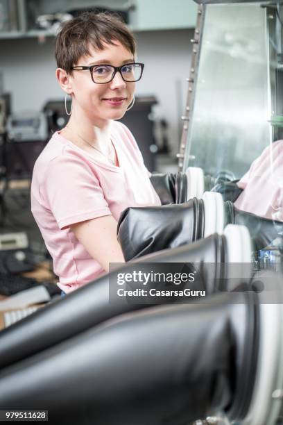 smiling female researcher using glove box for measuring transient photocurrent in organic semiconductors - glove box stock pictures, royalty-free photos & images