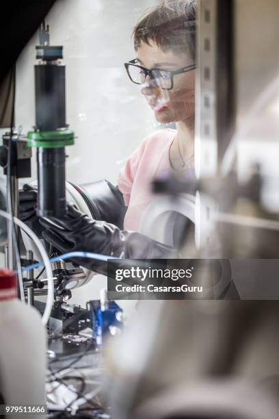 young female researcher preparing samples in glove box for measuring transient photocurrent in organic semiconductors - glove box stock pictures, royalty-free photos & images