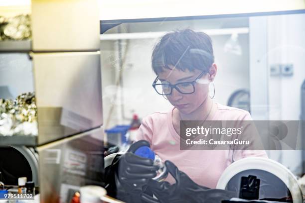 young female researcher preparing samples in glove box for measuring transient photocurrent in organic semiconductors - glove box stock pictures, royalty-free photos & images