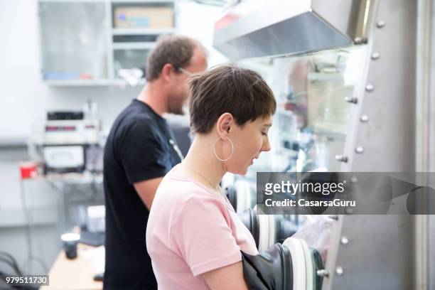 researchers working in organic semiconductors research laboratory - glove box stock pictures, royalty-free photos & images
