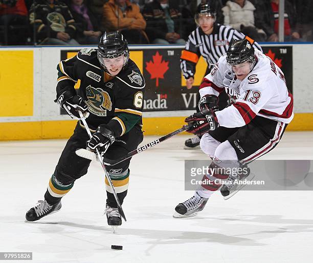 Peter Holland of the Guelph Storm tries to stick check Scott Harrington of the London Knights in the first game of the opening round of the 2010...