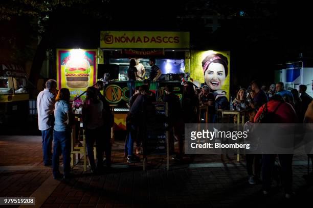 Customers eat next to a food truck at night in the Las Mercedes neighborhood of Caracas, Venezuela, on Friday, June 15, 2018. Las Mercedes, the...
