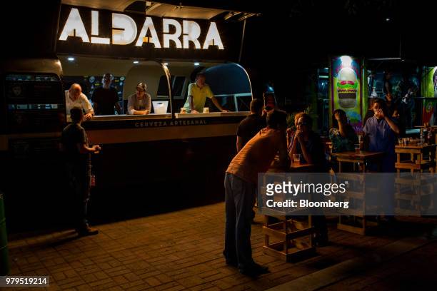 Customers drink next to a beer truck at night in the Las Mercedes neighborhood of Caracas, Venezuela, on Friday, June 15, 2018. Las Mercedes, the...