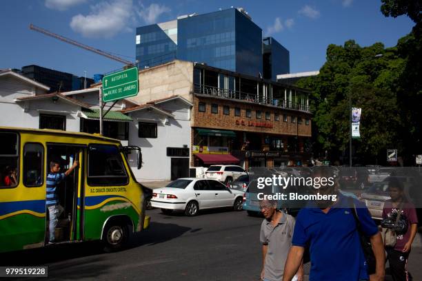 Pedestrians and traffic move along the main avenue as a newly constructed building stands in the Las Mercedes neighborhood of Caracas, Venezuela, on...