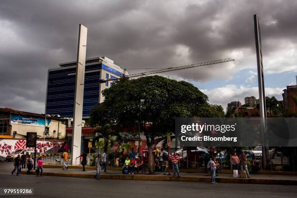 People wait at a bus stop as crane stands next to a newly constructed building in the Las Mercedes neighborhood of Caracas, Venezuela, on Thursday,...