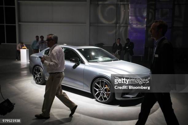 Attendees pass in front of the Volvo S60 vehicle on display during an unveiling event at the official opening of the Volvo Cars USA plant in...