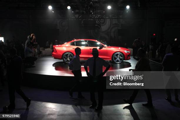 Attendees pass in front of a Volvo S60 vehicle on display during an unveiling event at the official opening of the Volvo Cars USA plant in...