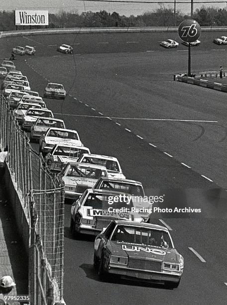 Buddy Baker leads Darrell Waltrip, Dale Earnhardt and the others around the opening lap. Baker would have an issue with his flywheel and leave the...