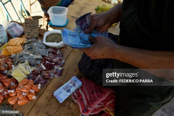 Man counts 1000-Bolivar-bills to buy groceries at the municipal market of Coche, a neighbourhood of Caracas, on June 20, 2018. Venezuelan President...