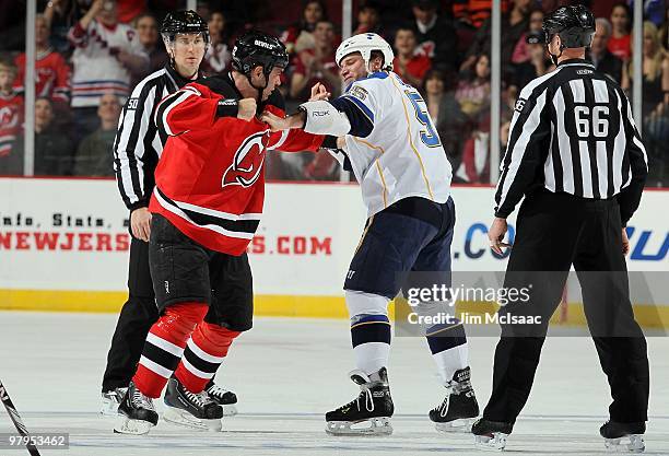 Cam Janssen of the St. Louis Blues trades punches with Pierre-Luc Letourneau-Leblond of the New Jersey Devils during their first period fight as...