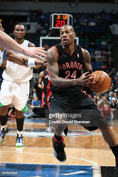 Sonny Weems of the Toronto Raptors drives towards the basket against Wayne Ellingtion and Kevin Love of the Minnesota Timberwolves during the game on...