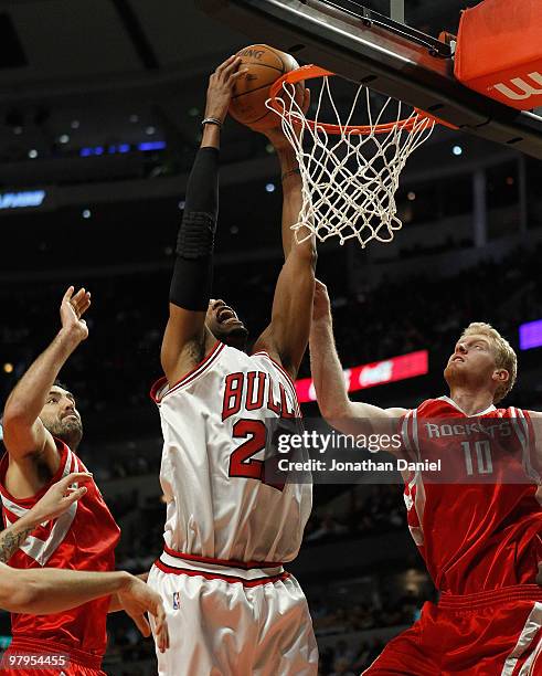 Taj Gibson of the Chicago Bulls goes up to dunk the ball between Luis Scola and Chase Budinger of the Houston Rockets at the United Center on March...