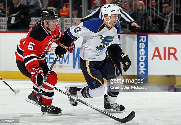 Andy McDonald of the St. Louis Blues skates against Andy Greene of the New Jersey Devils at the Prudential Center on March 20, 2010 in Newark, New...