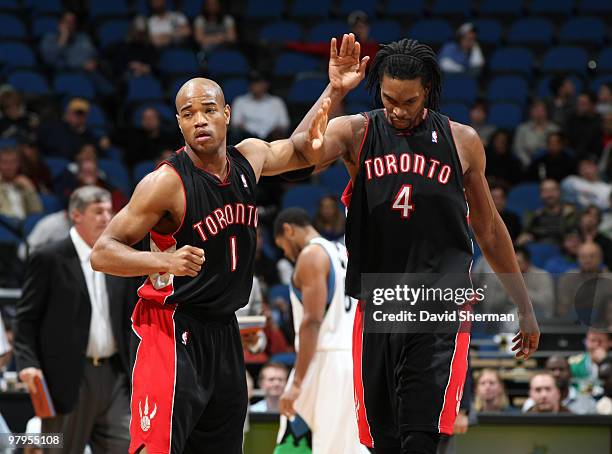 Jarrett Jack Chris Bosh of the Toronto Raptors give eachother a high-five as they walk back to the bench during the game against the Minnesota...