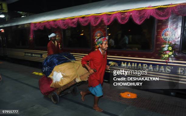 Lifestyle-India-tourism-rail-travel, FOCUS by Sailendra Sil A barefoot Indian porter pulls bags of supplies along the platform before the Maharajas'...