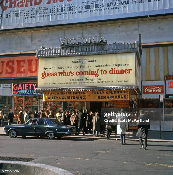 Cinema-goers line up outside the Victoria Theatre on Broadway in Times Square, New York, New York, December 1, 1967. The marquee advertises 'Guess...