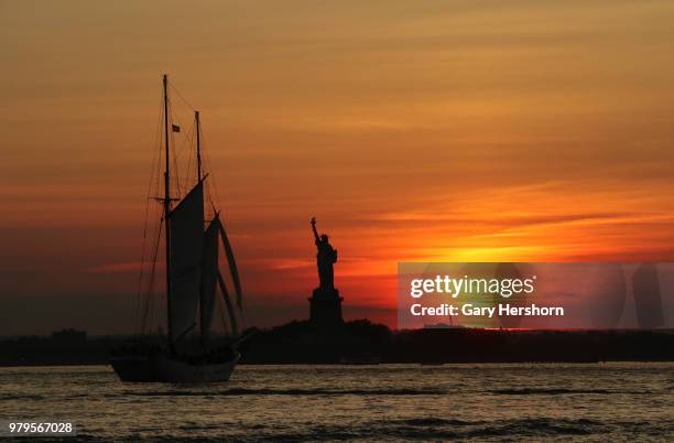 The sun sets behind the Statue of Liberty on June 17, 2018 in New York City.