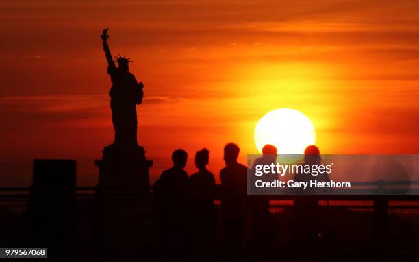 The sun sets behind the Statue of Liberty on June 17, 2018 in New York City.