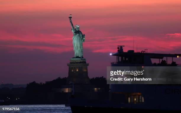 The sun sets behind the Statue of Liberty on June 17, 2018 in New York City.
