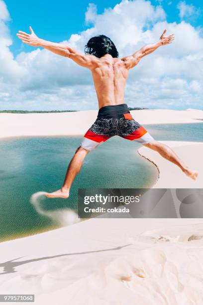 若い男の lençois maranhenses の砂丘から飛び降りる - standing water ストックフォトと画像