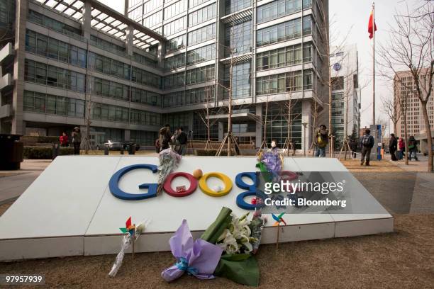Flowers are placed on a sign outside the Google Inc. Office in Beijing, China, on Tuesday, March 23, 2010. Google Inc., following through on a pledge...