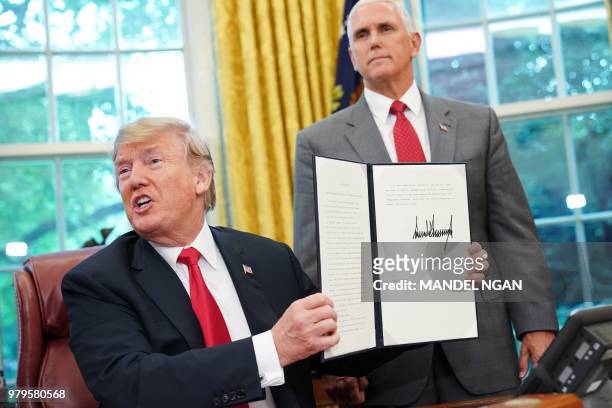 Watched by Vice President Mike Pence, US President Donald Trump shows an executive order on immigration which he just signed in the Oval Office of...