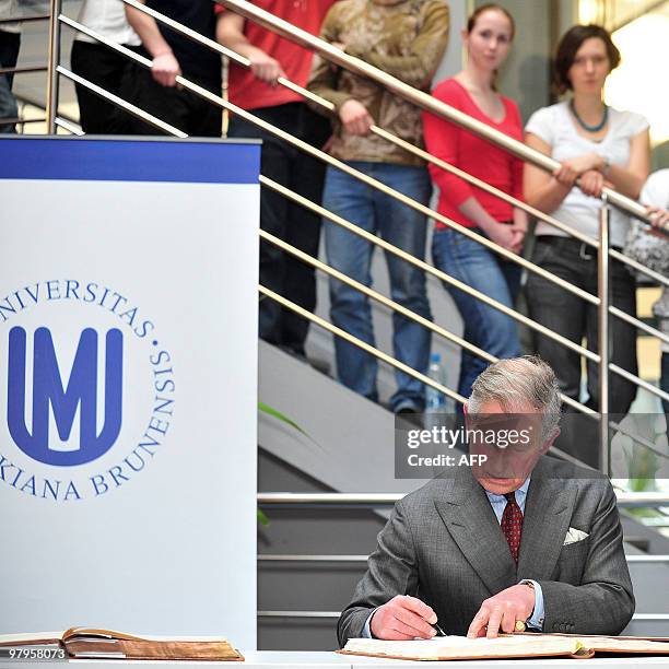 Britain's Prince Charles signs an autograph in a university visitors book as a students behind look on during his visit to Masaryk University in...