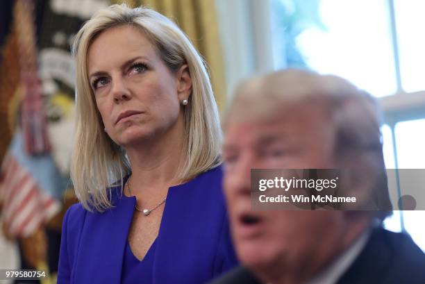 Department of Homeland Security Secretary Kirstjen Nielsen listens as U.S. President Donald Trump answers questions after signing an executive order...