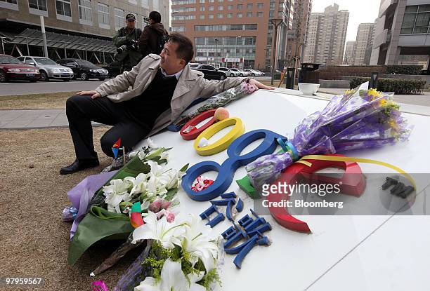 Man poses for a photograph next to the Google Inc. Sign outside the company's offices in Beijing, China, on Tuesday, March 23, 2010. Google Inc.,...